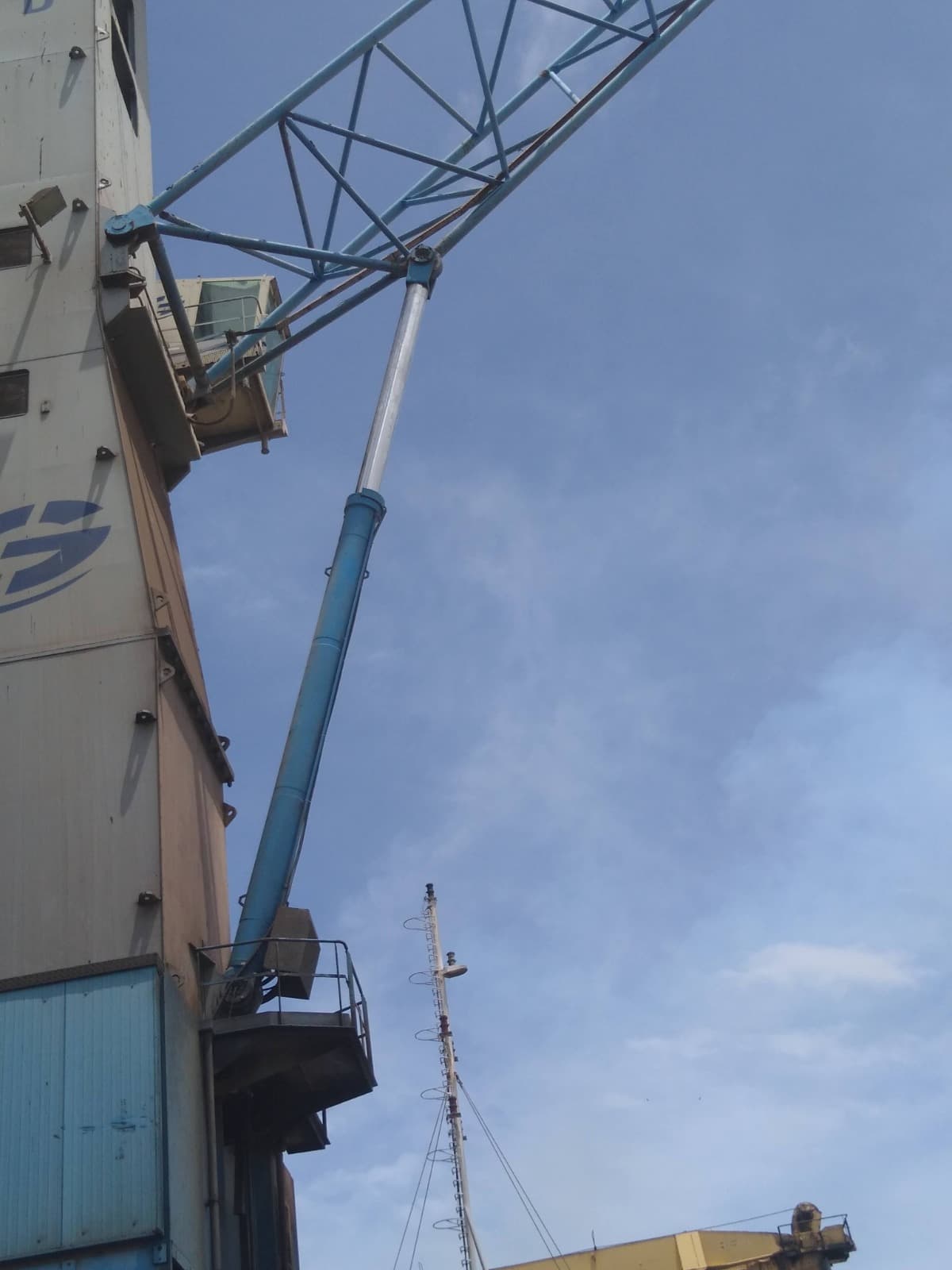 Low-angle view of a port crane boom against a blue sky