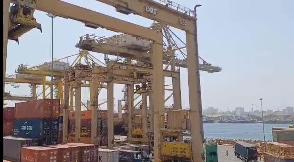 Container gantry cranes at a port with the city skyline behind